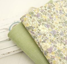 the fabric is green and white with flowers on it, as well as other fabrics