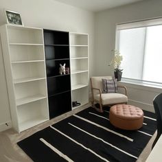 a living room with a black and white rug on the floor next to a book shelf