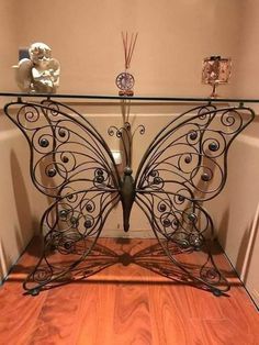 a metal butterfly table with glass top in a corner next to a white wall and wooden floor