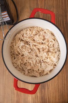 a pan filled with shredded meat on top of a wooden table