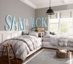 a bedroom with two twin beds and a gray rug in front of the bed is decorated with blue letters that spell out sam & jack