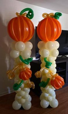 balloon decorations in the shape of pumpkins and vines on a wooden floor next to a flat screen tv