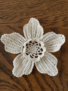 a crocheted flower sitting on top of a wooden table