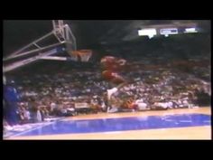 a basketball player jumping up into the air to dunk a ball in front of an audience