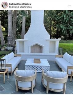 an outdoor living room with white furniture and a fireplace