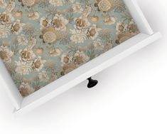 an open white box with floral wallpaper on the lid and drawer underneath it, in front of a white background