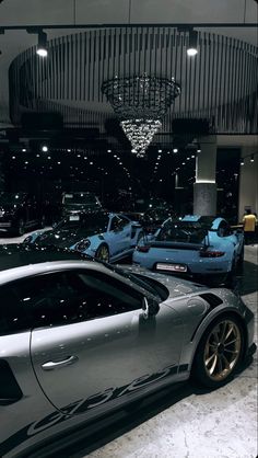 a bunch of cars are parked in a showroom with chandelier above them