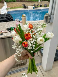 a person holding a bouquet of flowers in front of a swimming pool with the door open