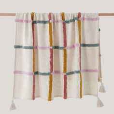 a white curtain with multicolored stripes hanging on a clothes line