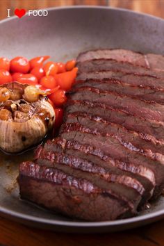 steak, mushrooms and tomatoes in a pan on a wooden table with a red heart shaped pepper