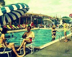 people are sitting at the edge of a swimming pool while others swim in the water