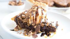 a piece of chocolate pie on a white plate with other desserts in the background