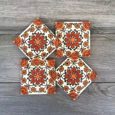 four orange and white tile coasters sitting on top of a wooden table