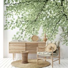 a room with a chair, table and tree mural on the wall next to it