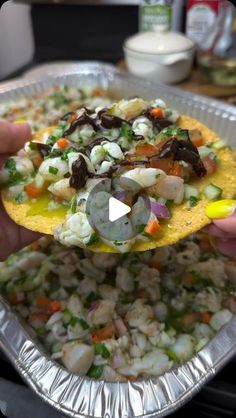 someone holding up a tortilla with shrimp and vegetables