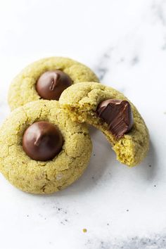 two cookies with chocolate chips and one is broken in half on a marble countertop