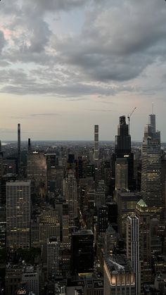 the city skyline is lit up at night with dark clouds in the sky over it