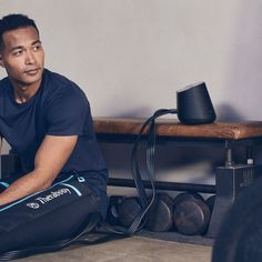 a man sitting on the ground with a gym bag in front of him, looking at the camera