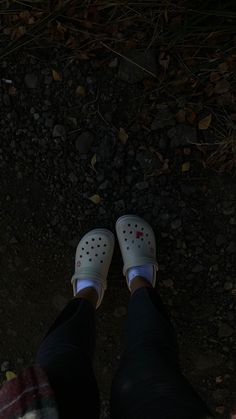 the person is wearing white shoes and standing in front of some leaves on the ground