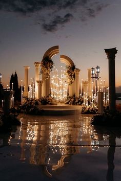 the entrance to an outdoor wedding venue lit up at night with candles and floral arrangements