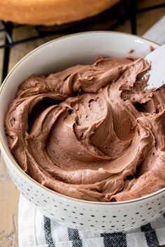 a white bowl filled with chocolate frosting on top of a table