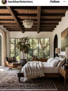 a bedroom with a large bed and lots of windows in the wall, along with an area rug on the floor