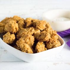 a white bowl filled with fried food next to a purple ribbon