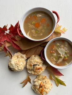 three bowls of soup and biscuits on a white surface with autumn leaves around them,