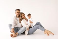 a man and woman are sitting on the floor with their baby in their arms, posing for a photo