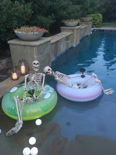 two inflatable skeleton floats sitting next to a pool