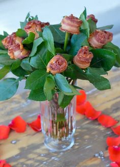 a vase filled with lots of flowers on top of a wooden table next to hearts