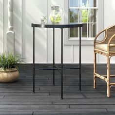 two chairs and a table on a wooden floor next to a white building with windows