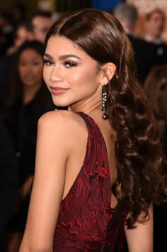 a woman with long brown hair in a red dress and large earrings on her head