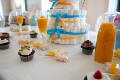 a table topped with lots of cupcakes and drinks