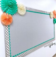 a mirror with some paper flowers on the edge and an orange flower in the middle