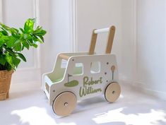 a wooden toy car sitting next to a potted plant in a room with white walls