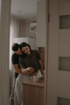 a man and woman are hugging in the kitchen