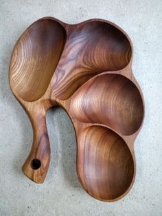 three wooden spoons sitting on top of a white floor next to each other in the shape of an elephant's tail