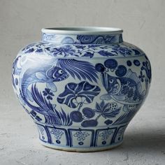 a large blue and white vase sitting on top of a table next to a wall