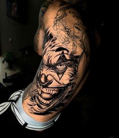 a man with tattoos on his arm has a creepy clown face and is wearing a tie