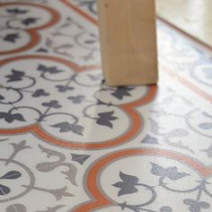 a piece of wood sitting on top of a floor next to an orange and white tile