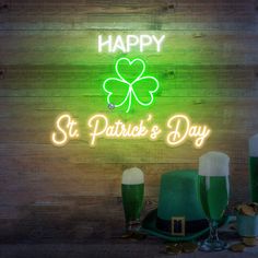 a neon sign that says happy st patrick's day next to two glasses of beer