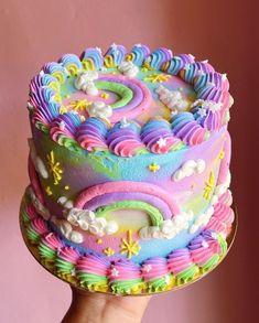 a hand holding a cake decorated with colorful icing