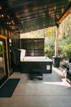 a hot tub sitting on top of a cement floor next to a wooden structure with lights hanging from it