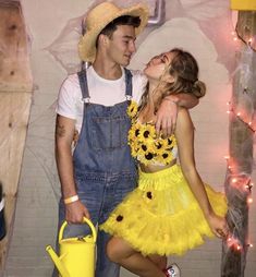 a man and woman dressed up as flower power couple kissing each other in front of a brick wall