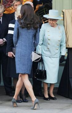 two women in blue dresses and hats are walking out of a building with other people