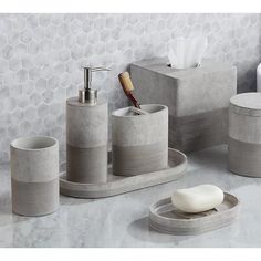 bathroom accessories including soap dispenser, toothbrush holder and soap dish on marble countertop