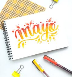 a notebook with the word mayo written on it next to some markers and pencils