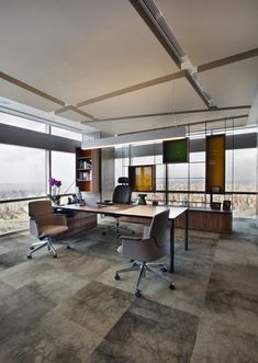 an office with large windows and desks on the floor, overlooking a cityscape