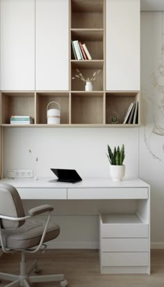 a white desk with a laptop computer on top of it next to a chair and bookshelf